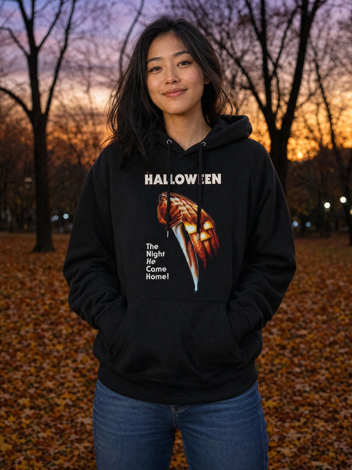 Woman wearing the officially licensed Halloween This Is Halloween hooded sweatshirt in an autumn park at dusk. AI-generated lifestyle image.