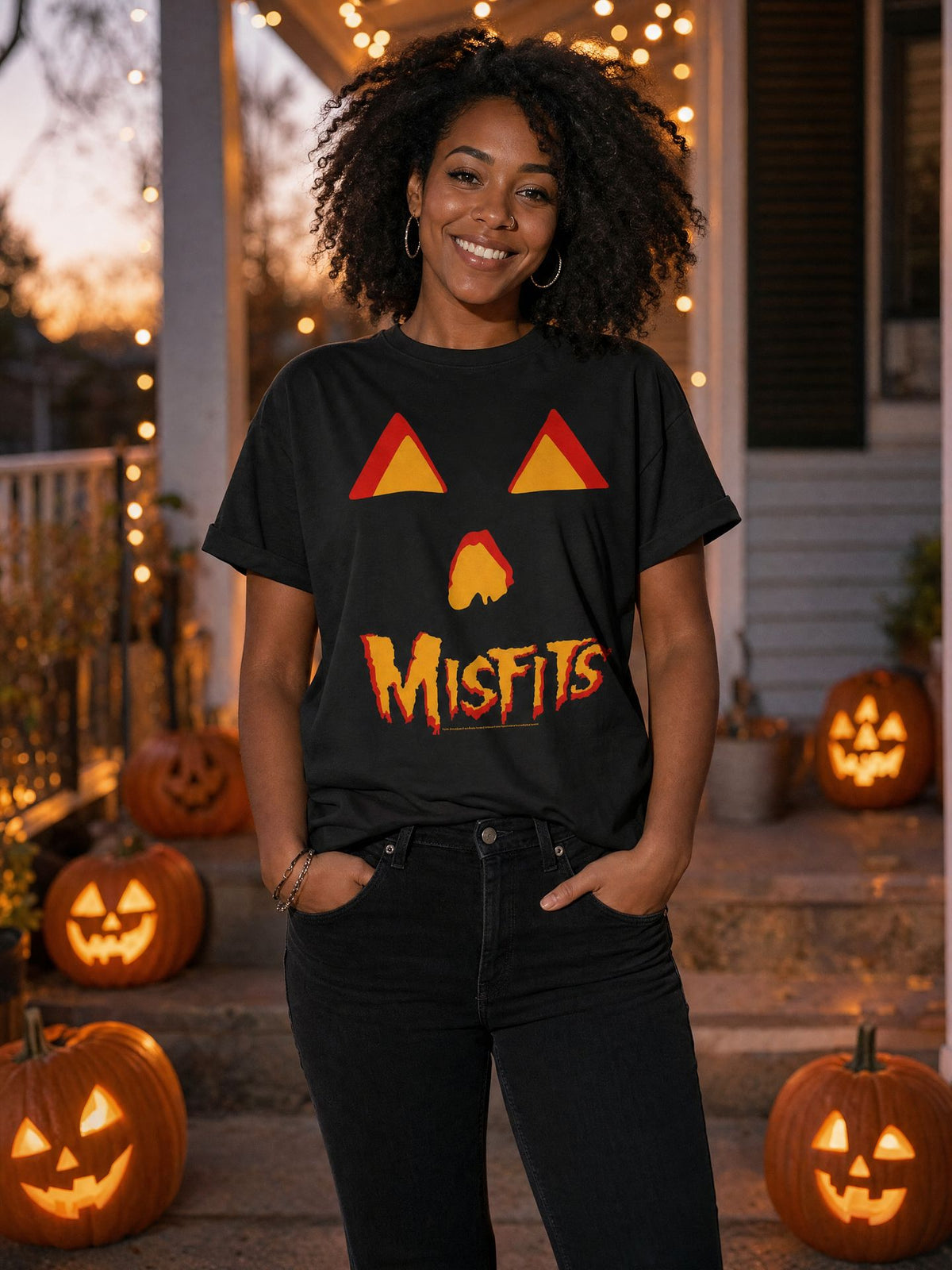 Woman wearing the officially licensed Misfits Jack O Lantern T-shirt on a Halloween porch at dusk. AI-generated lifestyle image.